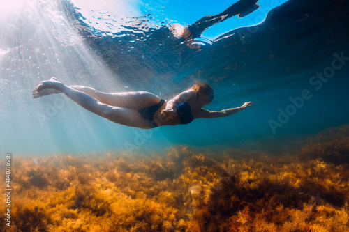 Young woman in bikini swimming and dive underwater in blue sea. Activity summer days at ocean