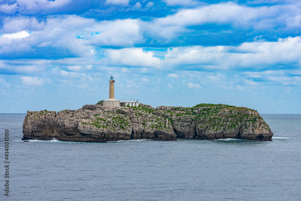 close view of a rock islet in the sea with a lighthouse