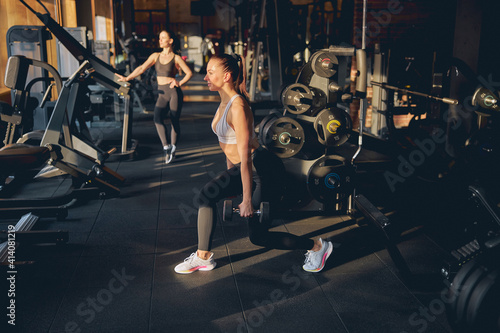 Smiling young woman doing lunges with weights