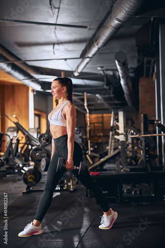 Merry young woman spending active time in gym