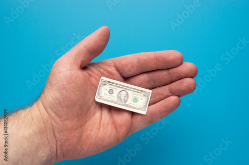 Toy tiny hundred dollar bill in open palm of a man, financial concept