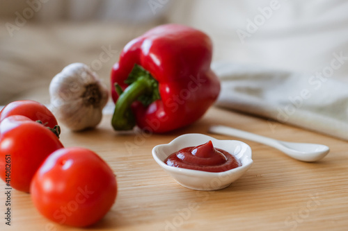 Ketchup or tomato sauce in a bowl, whole tomatoes, garlic close-up