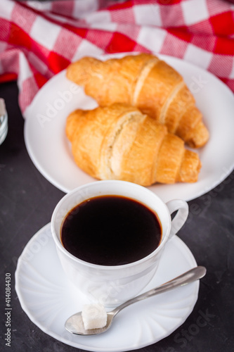 delicious fresh croissant and cup of coffee on a dark stone rustic background