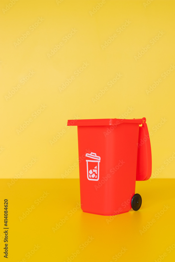 Red garbage container on yellow background Red garbage container on yellow background
