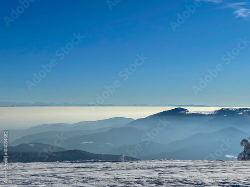 View of a distant mountain range (the Alps) from other snow-capped mountains (the Vosges) with a sea of clouds © Mickaël LEBRET