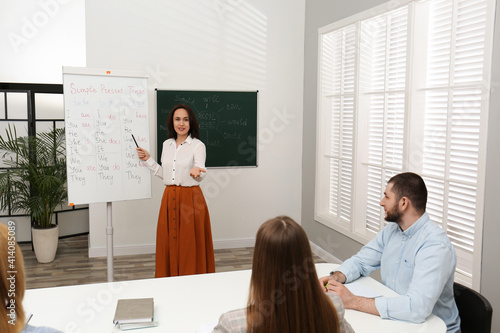 Foto English teacher giving lesson on simple present tense near whiteboard in classro