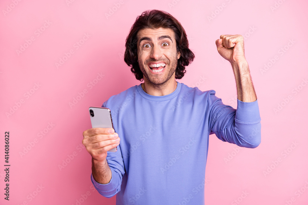 Portrait of hooray guy hold telephone hand fist wear purple sweater isolated on pastel pink color background Portrait of hooray guy hold telephone hand fist wear purple sweater isolated on pastel pink color background