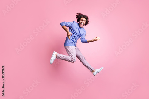 Full size photo of young positive handsome crazy excited smiling man jump play invisible guitar isolated on pink color background