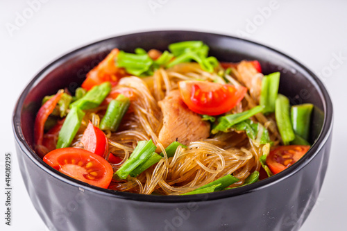 delicious glass noodles with chicken and vegetables on a white acrylic background