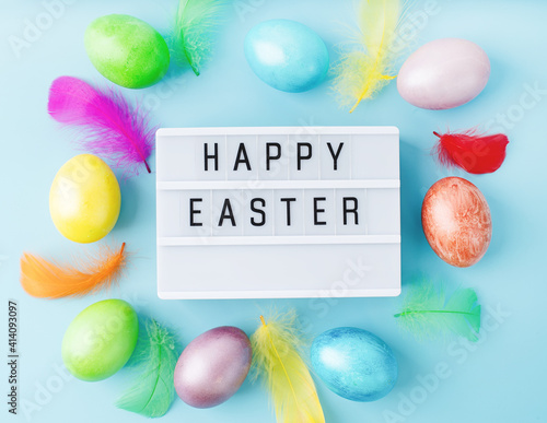 Top view Happy Easter light box decorated with bright colored eggs and feathers photo