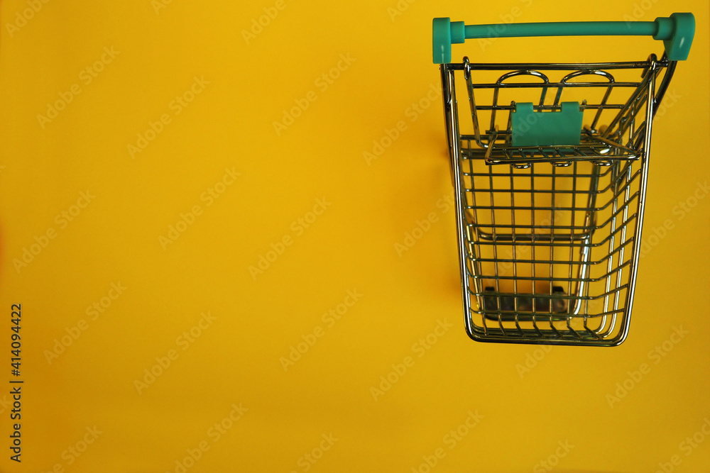close up a small metal cart with a supermarket on a yellow background top view . sales close up a small metal cart with a supermarket on a yellow background top view . sales