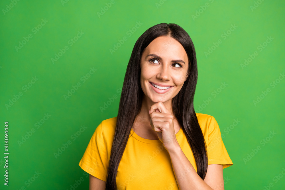 Photo of young woman happy positive smile dream dreamy think look empty space hand touch chin isolated over green color background Photo of young woman happy positive smile dream dreamy think look empty space hand touch chin isolated over green color background