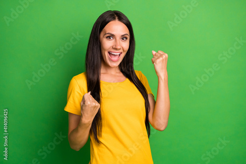 Photo of charming happy young woman raise fists win wear yellow t-shirt isolated on bright green color background