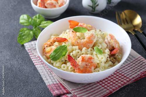 Italian ditalini pasta with shrimps and basil in a white bowl on a dark background