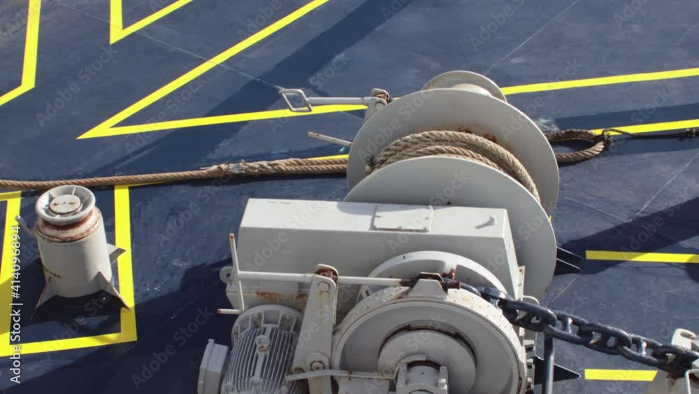 Large thick mooring rope being winched across the deck of a boat ship