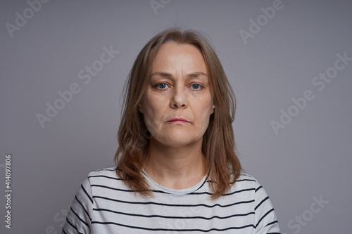 Close up portrait of serious middle aged woman. Studio shot over gray background.