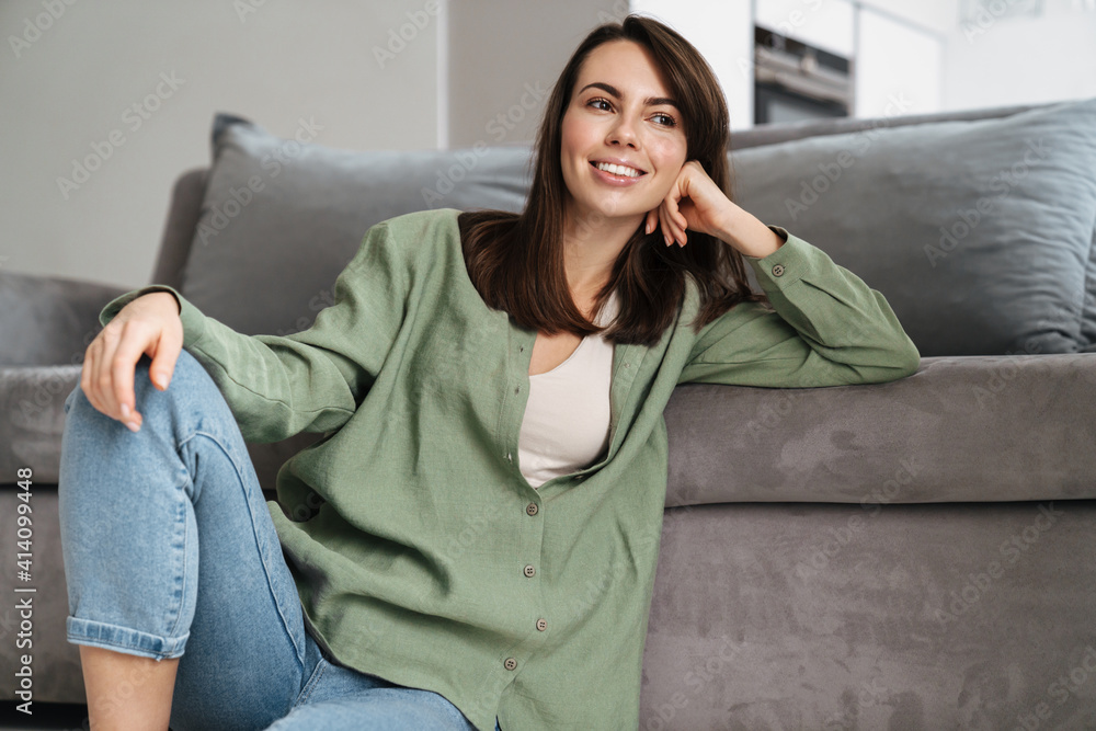 Obraz premium Cheerful beautiful woman smiling at camera while sitting on floor