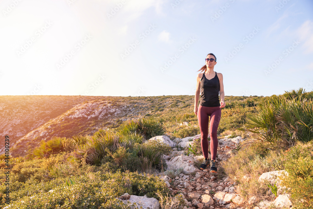Fit woman walking on the mountain near the sea at sunrise . Healthy lifestyle concept