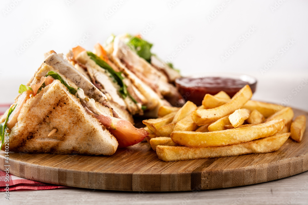 Club sandwich and French fries with ketchup sauce on wooden table Club sandwich and French fries with ketchup sauce on wooden table