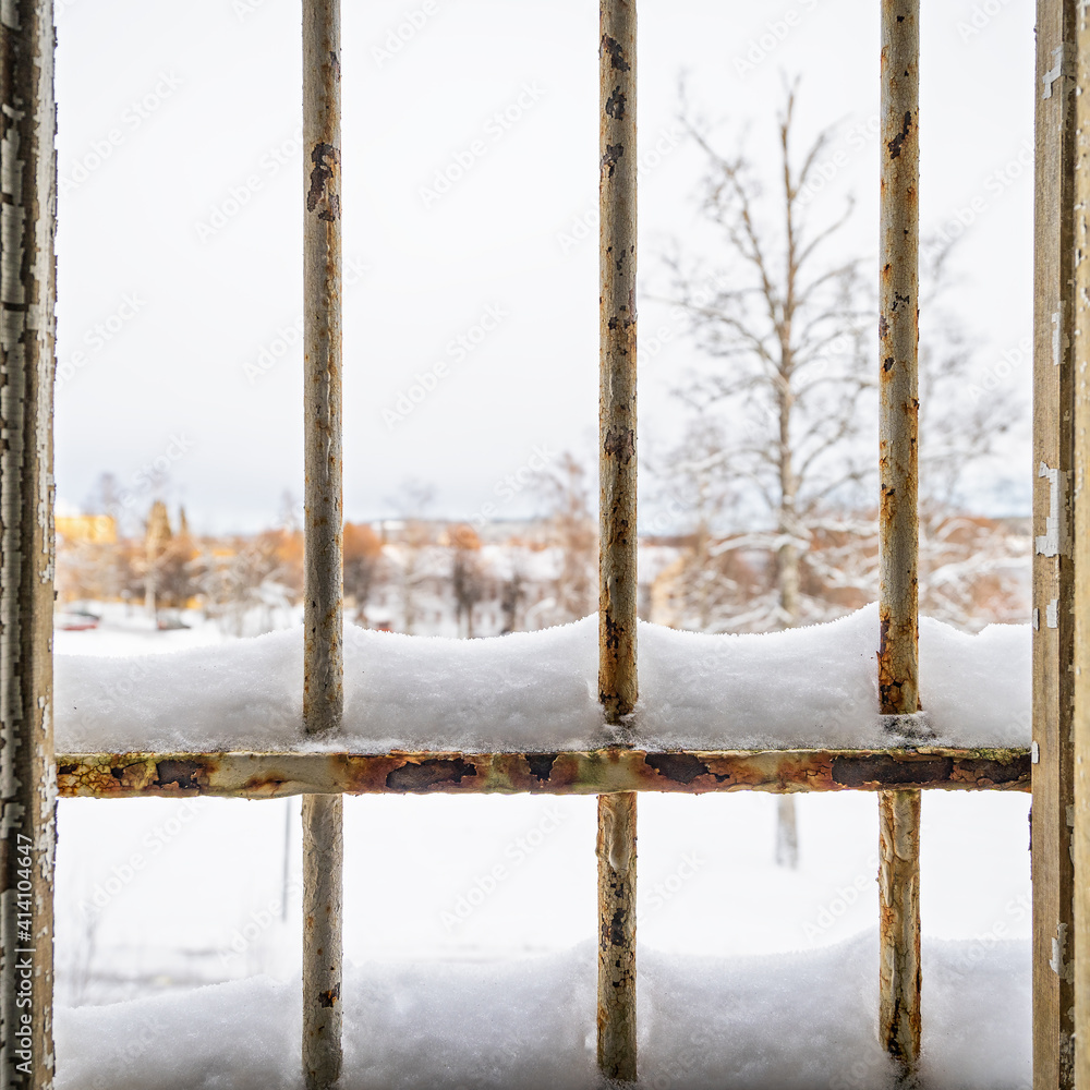 Winter view through a broken prison window with snow covered rusty metal bars Winter view through a broken prison window with snow covered rusty metal bars