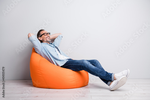 Full body profile side photo of man happy positive smile sit bag rest relax look empty space isolated over grey color background photo
