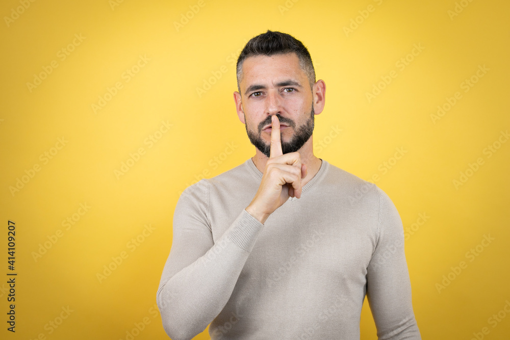Handsome man with beard wearing sweater over yellow background asking to be quiet with finger on lips. Silence and secret concept. Handsome man with beard wearing sweater over yellow background asking to be quiet with finger on lips. Silence and secret concept.