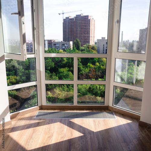 Panoramic window. Underfloor heater grill. Sharp shadows from the panoramic window frame on the wooden floor