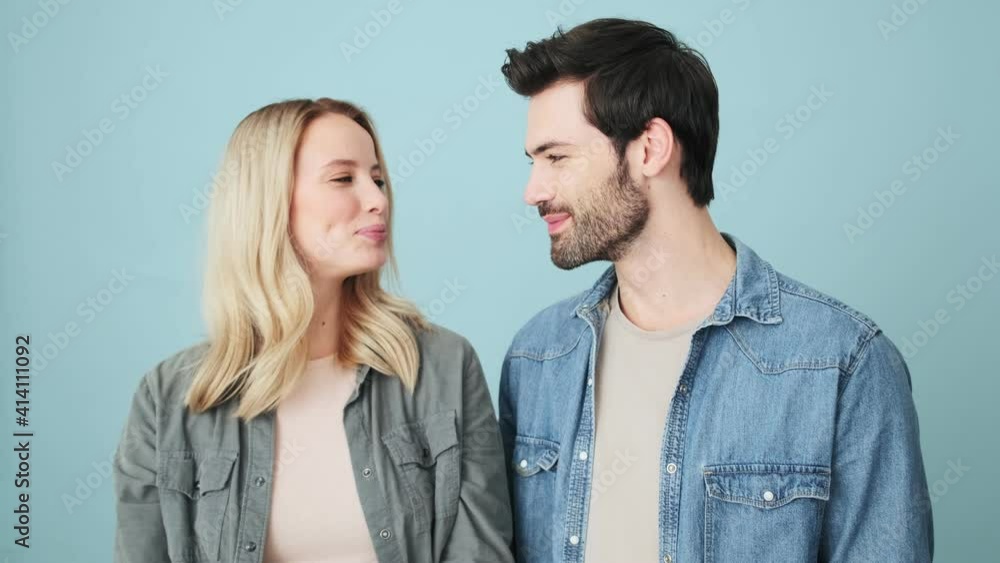 Pleased couple man and woman are showing ok gesture to the camera while standing isolated over blue background in studio Pleased couple man and woman are showing ok gesture to the camera while standing isolated over blue background in studio