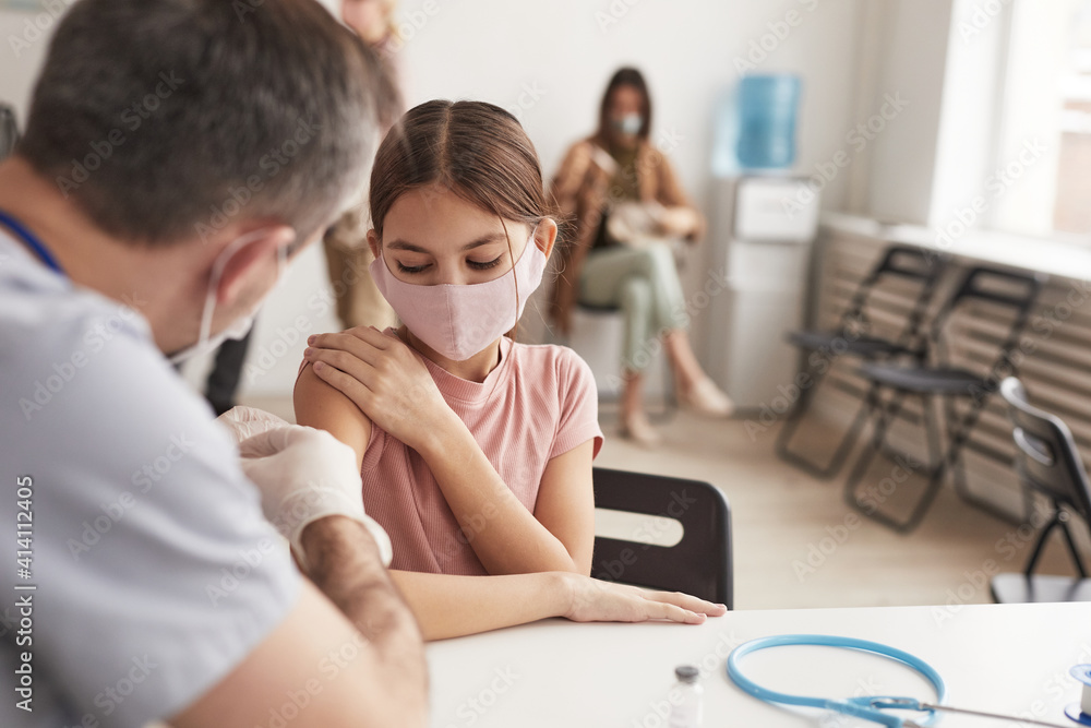 Obraz premium Portrait of unrecognizable doctor vaccinating cute little girl in medical clinic, copy space