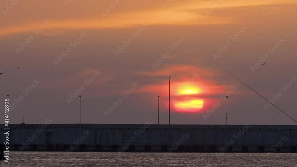 Silhouettes of women fishing on breakwater. Red sunset background. Port of Sochi, Russia. Silhouettes of women fishing on breakwater. Red sunset background. Port of Sochi, Russia.