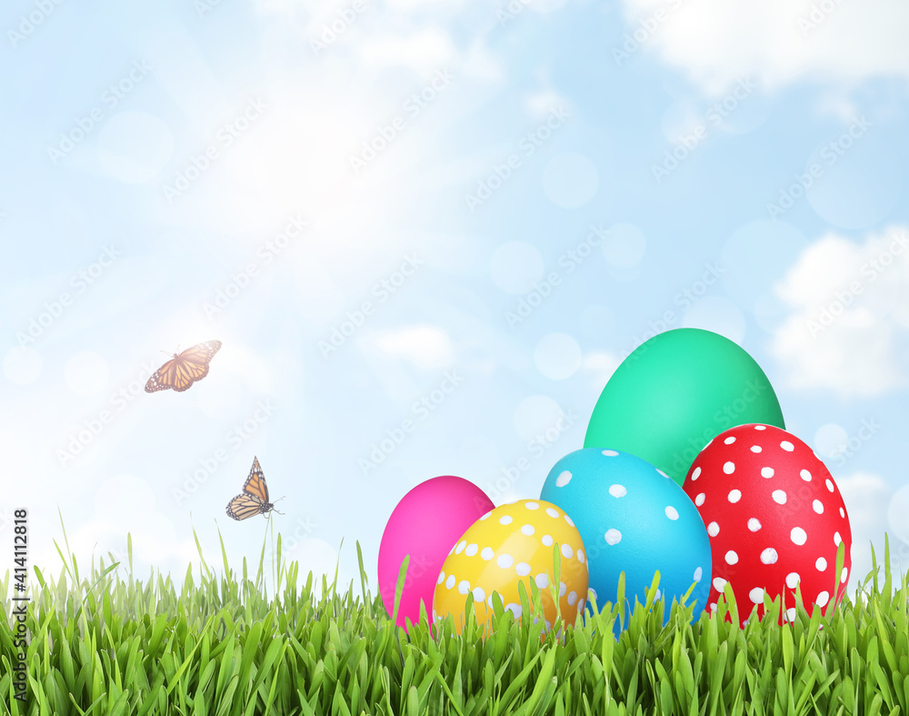 Bright Easter eggs on green grass outdoors, space for text