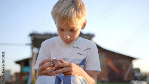 A little boy unfolds and eats a chocolate egg with toys.