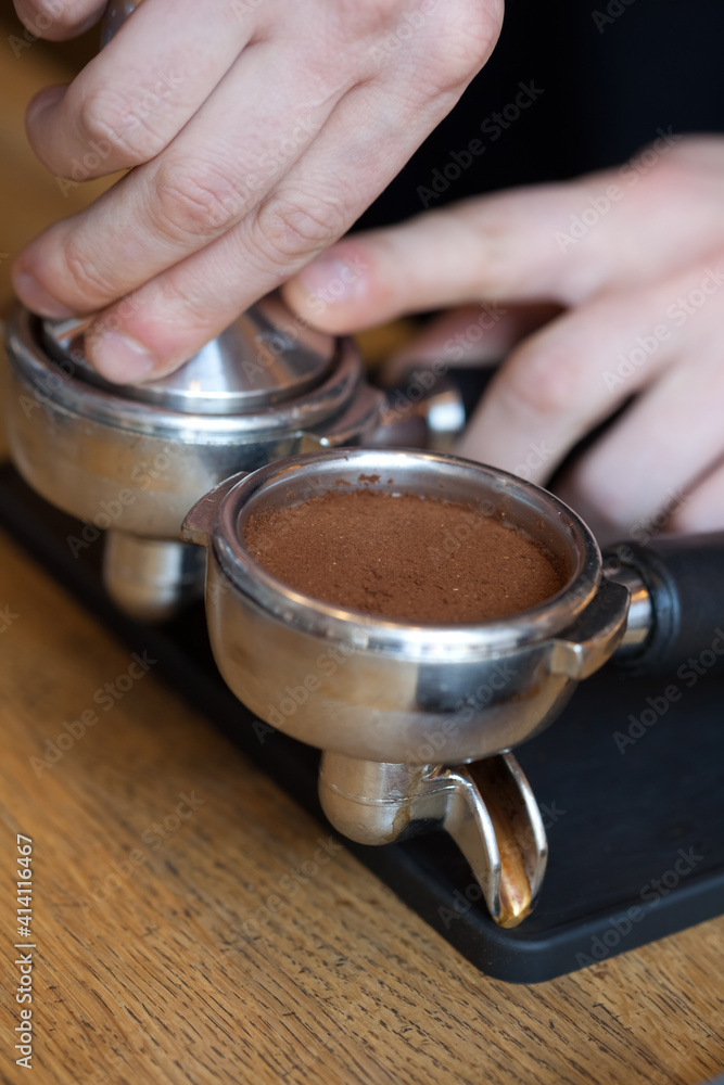 barista hands temping coffee grind in espresso holder