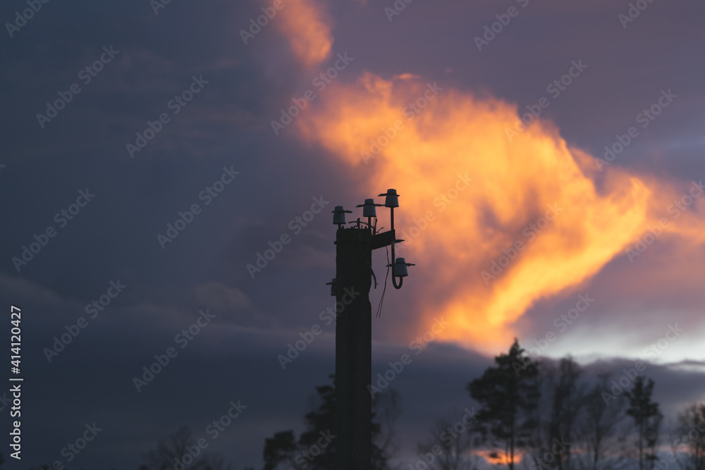 Golden hour with fire clouds. Beautiful sunset with trees. Electric pole with cut down wires.