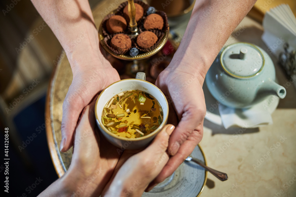Two people joing their hands and holding cup of tea Two people joing their hands and holding cup of tea