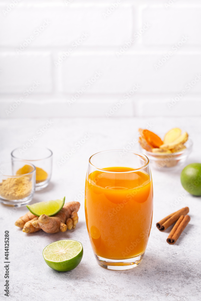 Healthy drink from turmeric and ginger roots and lime in a glass on white concrete background. Healthy drink from turmeric and ginger roots and lime in a glass on white concrete background.
