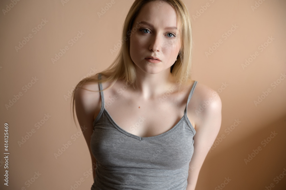 Graceful young woman posing against beige wall. Graceful young woman posing against beige wall.