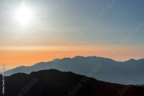 silhouettes of mountain ranges at sunrise background image