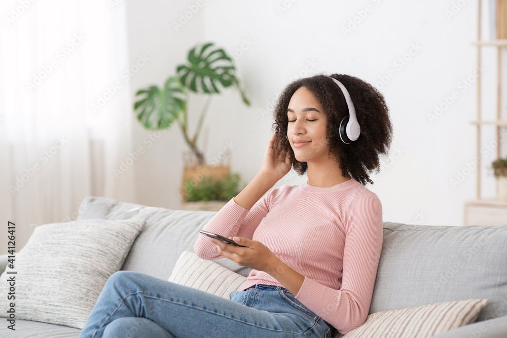 Happy funny lady with headphones sits in comfortable sofa, listening new pop music Happy funny lady with headphones sits in comfortable sofa, listening new pop music