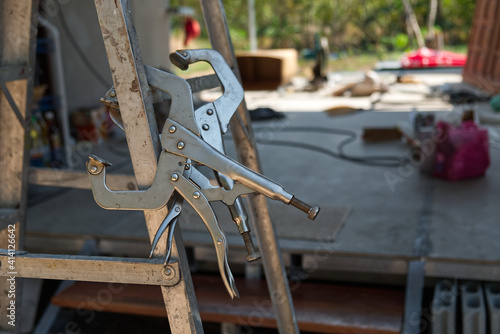 C-Clamp Locking Pliers on the Aluminum Folding Stairs in the Construction Site. 