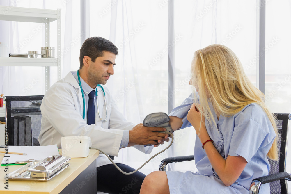 Fototapeta premium male doctor is putting a cuff of a blood pressure monitor on patient woman