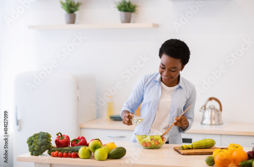 African Lady Cooking Vegetable Salad Standing In Modern Kitchen Indoors