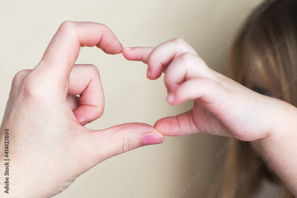 Heart shape created from little girl's hands and her mother's hands on beige background. Heart shape created from little girl's hands and her mother's hands on beige background.
