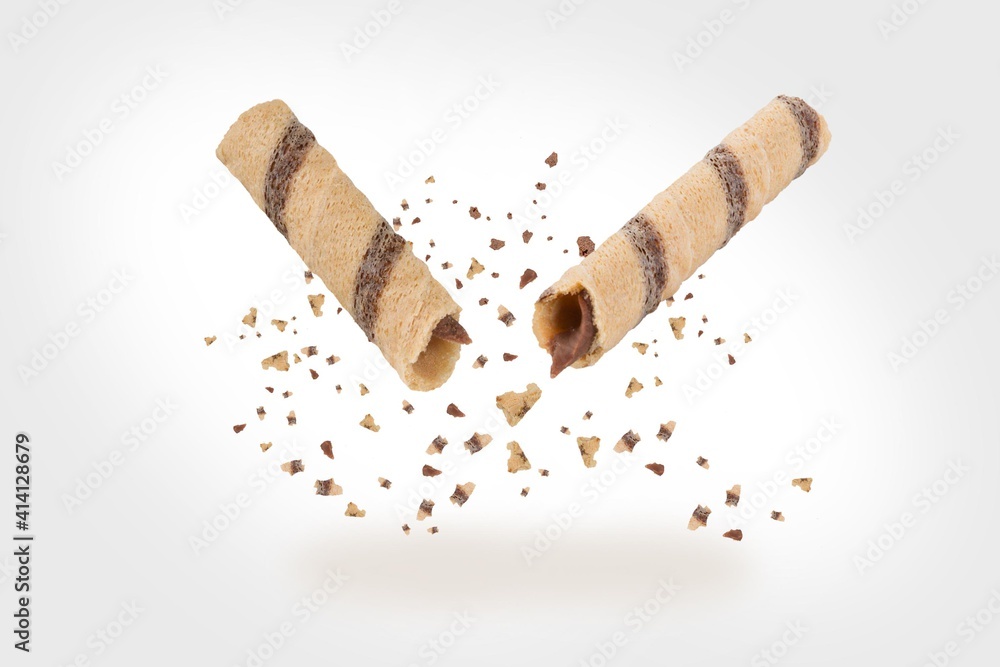 Delicious broken sweet waffle on grey background. Waffle rolls stick, flying Delicious broken sweet waffle on grey background. Waffle rolls stick, flying