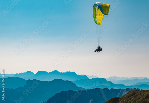 Beautiful alpine summer view with a paraglider and mountain silhouettes in the background at the famous Hochfelln summit, Bergen, Bavaria, Germany photo