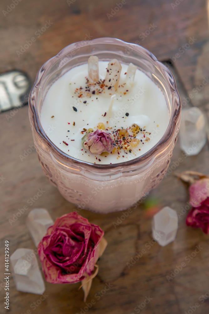 Soya candle with crystal quartz and rose decoration on vintage wooden table Soya candle with crystal quartz and rose decoration on vintage wooden table