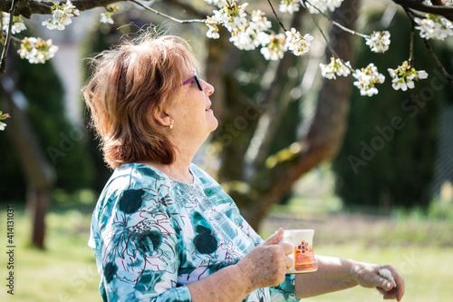 Quadro em tela Senior woman drinking coffee in blooming garden