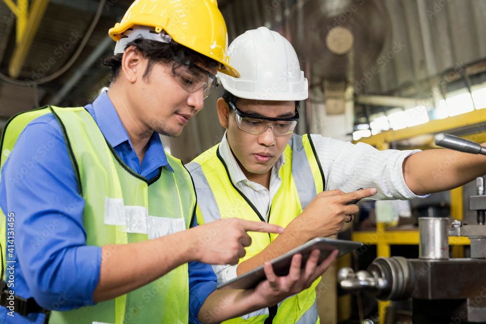 Engineers and skilled technicians are maintaining machinery. Professional technicians are holding a tablet to control work in industrial plants Engineers and skilled technicians are maintaining machinery. Professional technicians are holding a tablet to control work in industrial plants