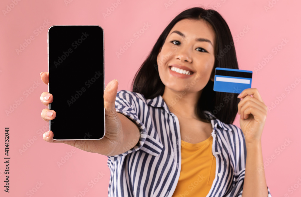 Asian lady showing blank smartphone screen and credit card Asian lady showing blank smartphone screen and credit card
