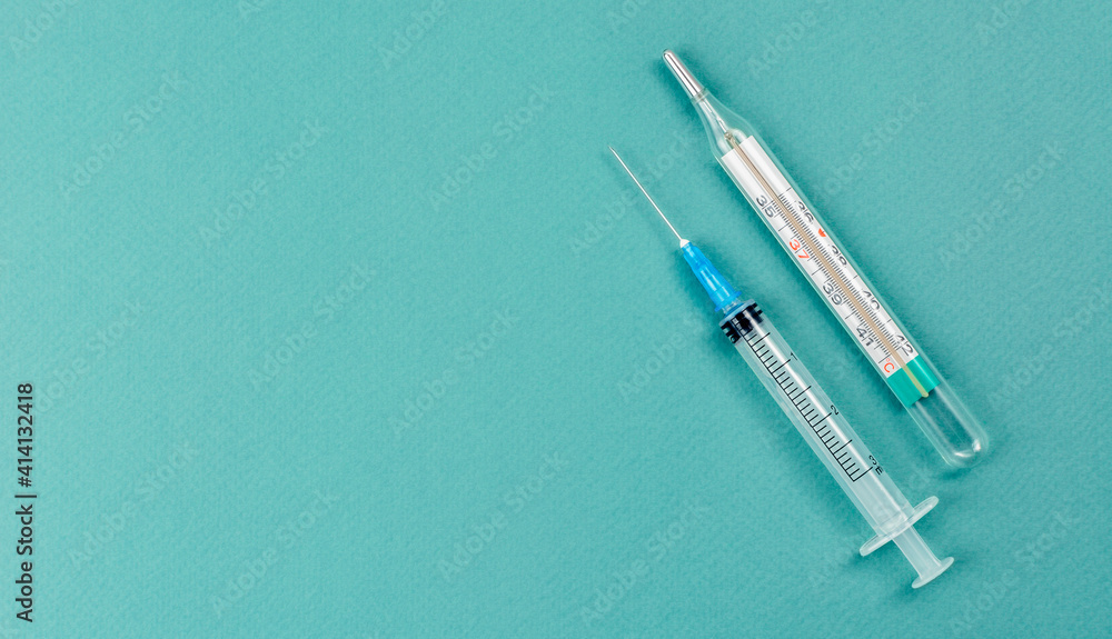 Syringe with mercury free thermometer. Coronavirus vaccine and injections concept. Lowering the temperature with injections. Syringe with mercury free thermometer. Coronavirus vaccine and injections concept. Lowering the temperature with injections.